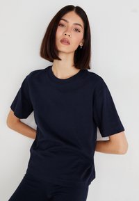 T-shirt blu navy a maniche corte con scollatura rotonda, realizzato in un tessuto morbido. Presenta una vestibilità rilassata e un design semplice e pulito.