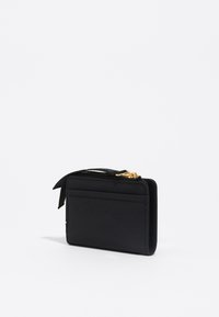 Cartera negra hecha de material suave. Cierre con cremallera y herrajes dorados. Presenta ranuras para tarjetas en un lado y un diseño plano.