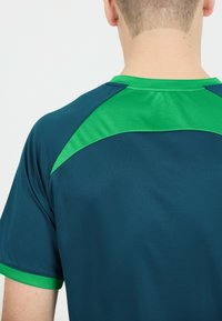 Mörk teal atletisk t-shirt med en grön detalj på axlarna och kragen. Slät, lättviktig tyg med design av rundad hals.