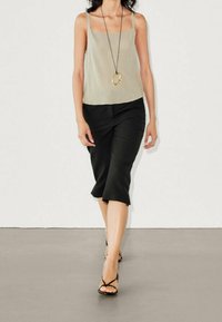 Beige värinen toppi, jossa ohuet hihnat, yhdistettynä mustaan midihameeseen, jossa kellotettu helma, ja mustiin remmisandaaleihin.