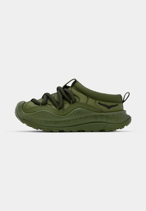 Green sneaker with a textured rubber sole, elastic laces, and a smooth fabric upper. Features rounded toe and subtle logo detail.