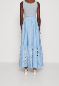 Ljusblått bomullsmaxikjol med broderade blommönster och hålstygn, med resårmidja och utsvängd lagerdesign.
