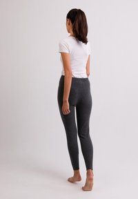 Grijze leggings van gebreide stof met een aansluitend ontwerp, voorzien van een hoge tailleband en een gladde textuur, gezien vanuit de achterkant.