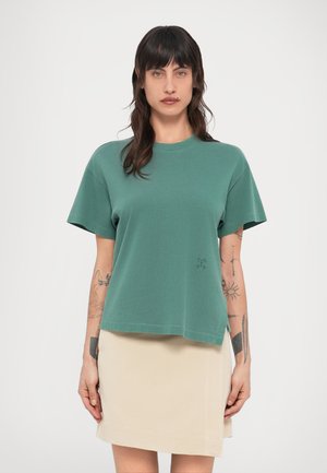 Πράσινο βαμβακερό μπλουζάκι με κοντά μανίκια, στρογγυλή λαιμόκοψη και άνετη εφαρμογή. Διαθέτει μικρή λεπτομέρεια λογότυπου στην αριστερή πλευρά μπροστά.