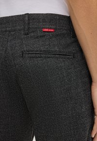 Czarno-białe spodnie w kratę o gładkiej fakturze, z tylną kieszenią i czerwoną metką z napisem "JOOP JEANS".