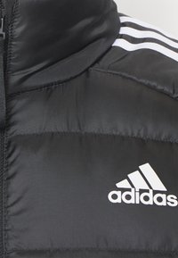 Crna podstavljena jakna s visokim ovratnikom, s bijelim Adidas logotipom i tri bijele pruge na ramenima. Glatka, sjajna tekstura tkanine.