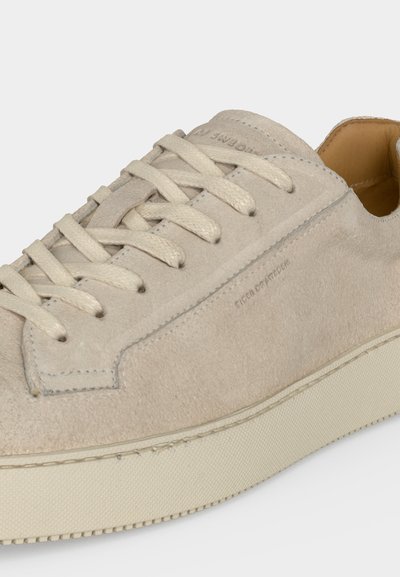 Ανοιχτό μπεζ σουέντ αθλητικό παπούτσι με ταιριαστά κορδόνια, χοντρή κρεμ καουτσούκ σόλα και απαλό ταμπά δερμάτινο εσωτερικό επένδυμα.