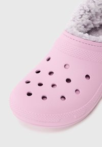 Helle rosa Slippers mit Belüftungslöchern und weichem, plüschigem Innenfutter, entworfen für Wärme und Komfort.