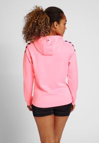 Spožs rozā kapucis ar kapuci, garām piedurknēm un melniem akcentiem uz pleciem. Izgatavots no mīksta, elastīga auduma.