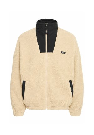 Beige fleece jacket with black nylon accents, high collar, full zip, and side pockets; texture appears soft and fluffy.
