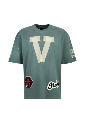 Blågrøn oversize T-shirt med stort hvidt tape-V foran, en rød stjernepatch, "Italy" tekst og nummer 69 på ærmerne.
