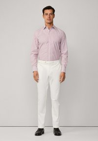 Pruhovaná košile s dlouhým rukávem v červené a bílé barvě, spárovaná s bílými kalhotami. Černé boty dokončují vzhled. Jednoduchý, upravený střih.