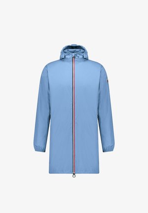 Imperméable bleu clair avec capuche, fermeture éclair intégrale avec des accents rouges et noirs, et poignets élastiques.