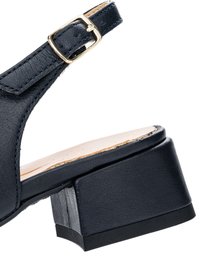 Sandalo alla caviglia in pelle nera con fibbia dorata e tacco largo a blocco, primo piano che mostra le cuciture e la suola testurizzata.