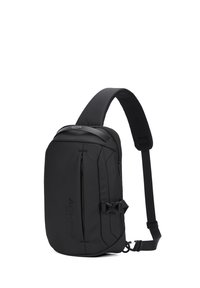 Zaino a tracolla nero realizzato in tessuto resistente, dotato di un compartimento principale con zip, tracolla regolabile e design minimalista con accento del logo.