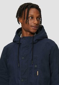 Marine blauwe hooded jack met een rits- en drukknoopsluiting, voorzien van een patch pocket en trekkoorden op de capuchon. Textuurafwerking van de stof.