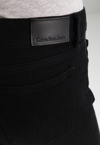 Los jeans de mezclilla negra cuentan con una textura suave, con un parche de cuero de Calvin Klein Jeans en la cinturilla y detalles de costura sutiles.