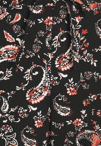 Black fabric featuring a paisley pattern in white and red, with floral accents; smooth texture and bow detail at the neckline.