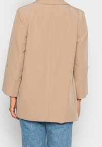 Beige blazer with a tailored fit, featuring a lapel collar and 3/4 sleeve length, accented by small silver buttons on the sleeves.