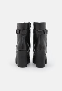 Černé kožené kotníkové boty se čtveratým podpatkem, s elegantním designem, bočními zipy a nastavitelnými popruhy kolem kotníku.