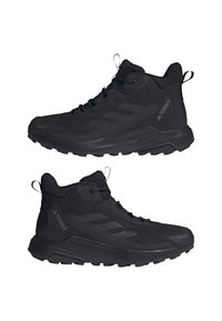 Chaussures de randonnée Adidas Terrex montantes noires avec semelle texturée, fermeture à lacets et languettes aux talons et à la languette, vues de côté.