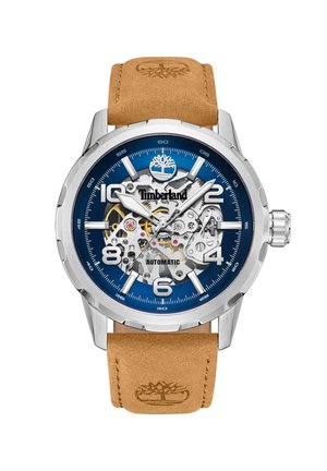Montre automatique Timberland avec un cadran bleu, un boîtier en argent et un bracelet en cuir marron. Présente des mécanismes exposés et des index heures audacieux.