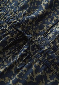 Nahaufnahme von blau-beigem gemustertem Stoff mit elastischem Bund und gebundener Kordel.