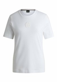 T-shirt bianco in cotone con maniche corte, caratterizzato da un sottile logo ricamato al centro. Collo a giroclassico con una texture liscia.