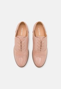 Scarpe di tela rosa chiaro con lacci, caratterizzate da una combinazione di pelle verniciata e camoscio, con punta arrotondata e dettagli di cucitura a contrasto.
