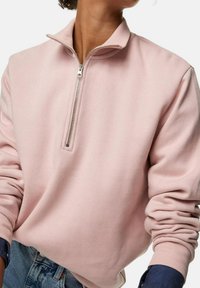 Lichtroze sweatvest met rits van zachte stof, voorzien van een opstaande kraag, zilveren ritssluiting en geribbelde manchetten met een losse pasvorm.