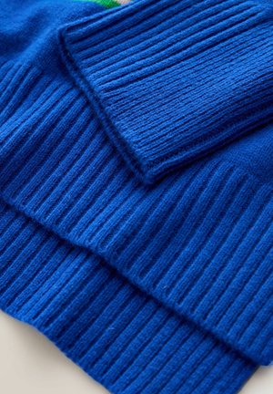 Gefalteter blauer gerippter Strickstoff, der eine detaillierte Textur und Naht in Nahaufnahme zeigt.