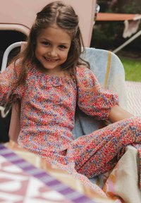 Kleurrijke jumpsuit met bloemenpatroon in roze, blauw en oranje tinten. Kenmerken zijn pofmouwen, een geplooide halslijn en een relaxed fit.