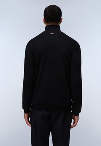 Zwarte pullover met een hoge kraag en geribde boorden, met een logo detail op de achterkant van de hals. Glad gebreide textuur, relaxed fit.