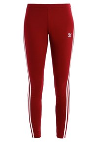 Röda träningsleggings med vita sidostrandningar, tillverkade av ett slätt, elastiskt material. Har Adidas-logotypen i vitt på vänster höft.