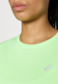 Αθλητική κοντομάνικη μπλούζα ανοιχτού πράσινου χρώματος με στρογγυλή λαιμόκοψη και μικρό γκρι λογότυπο στο στήθος. Λείο ύφασμα που απορροφά την υγρασία.