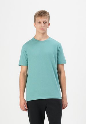 Lys teal bomulds t-shirt med rund hals og korte ærmer, der har en afslappet pasform og glat tekstur. Bæres med sorte bukser.