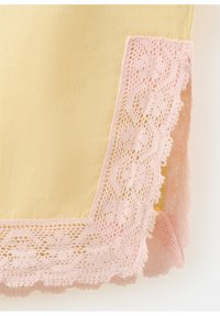 Tissu jaune avec une délicate bordure en dentelle rose ornée de motifs floraux le long des bords.