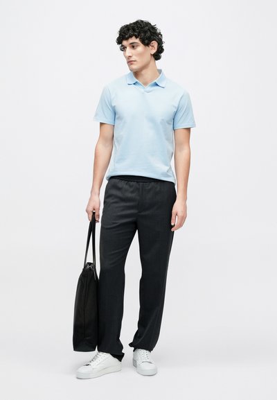 Gaiši zils polo krekls, tumši pelēkas bikses ar elastīgu jostasvietu, baltas sporta apavi un melna soma ar rokturiem. Gluda auduma, brīvs piegriezums, bez rakstiem.