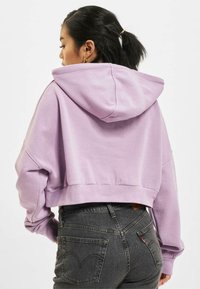 Gecombineerde hoodie van lichtpaars fleece, met een capuchon en een losse pasvorm. Gepaarde met donkerdere, slim-fit jeans met details op de achterzak.