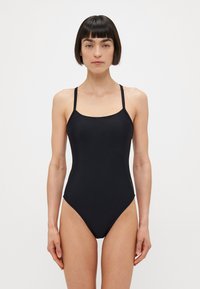 Zwarte tankini met dunne verstelbare bandjes, een ronde halslijn en een aansluitende snit, gemaakt van soepel, rekbaar materiaal.