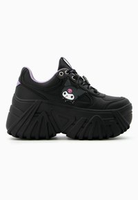 Black sneakers with a chunky sole, featuring a purple accent at the heel, and a cartoon character patch on the side. Textured leather material.