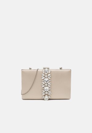 Rechteckige beige Clutch-Tasche mit einer vertikalen Reihe großer klarer Edelsteine und einem silbernen Kettenriemen vor weißem Hintergrund.