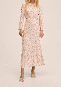 Vestido midi floral en rosa claro con mangas largas, escote fruncido, cortes laterales y un tejido suave y ligero cubierto de pequeñas flores de colores.