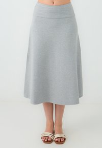 Grijze, knie-lange A-lijn rok van lichte stof, met een soepele tailleband en subtiele zijsplitten. Gecombineerd met sandalen met straps.
