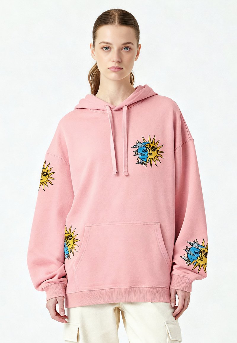 Rosa oversized hoodie med broderi av sol och måne i blått och gult. Har en framficka och dragsko i huvan. Mjukt material.