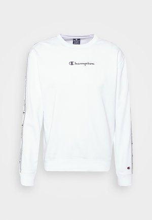 Hvid bomulds sweatshirt med lange ærmer, rund halsudskæring og "Champion" logo i sort på brystet og ned ad ærmet.