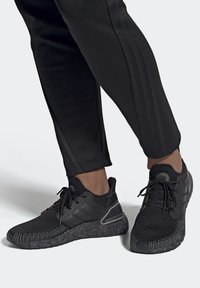 Scarpe da ginnastica nere con tomaia in maglia texturizzata, supporto per il tallone sagomato e suola in gomma con motivo. Abbinate a pantaloni neri a sigaretta.