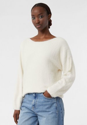 Weißer, flauschiger Pullover mit weitem Ausschnitt und langen Ärmeln, kombiniert mit hellblauen Jeans. Die Textur wirkt weich und gemütlich.