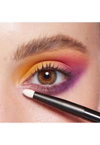Trucco per occhi colorato con sfumature di arancione, rosa e viola. Un pennello per trucco applica un colore luminoso e scintillante vicino alla palpebra inferiore.