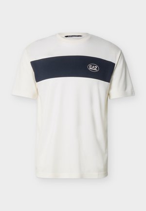 Bela majica s kratkimi rokavi in širokim črnim vodoravnim trakom čez prsni koš ter majhnim belim logotipom EA7 na levi strani.